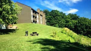 A building with a flat roof and multiple windows, surrounded by a grassy area with a picnic table and a lantern.