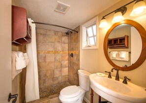 Een badkamer met een douche, toilet, wastafel en spiegel.