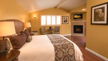 A bedroom with a large bed, a fireplace, and a view of the outdoors through the window.