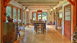 A spacious dining area with a wooden table and chairs, large windows, and a rustic ceiling. - House Belleayre peaceful spring water swimming pond (Fleischmanns)