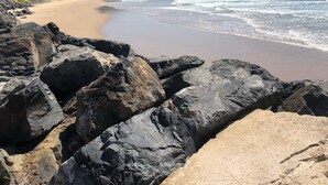 A beach with rocky foreground and a sandy shore. - Jetty Beach House (Coffs Harbour)