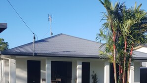 A modern house with a flat roof, a covered porch, and a well-maintained lawn.