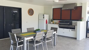 A modern kitchen with a built-in oven, a refrigerator, and a dining area with a table and chairs.