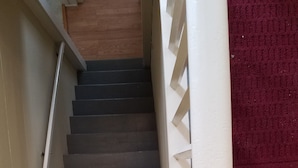 Un escalier avec une rampe blanche et des marches sombres.