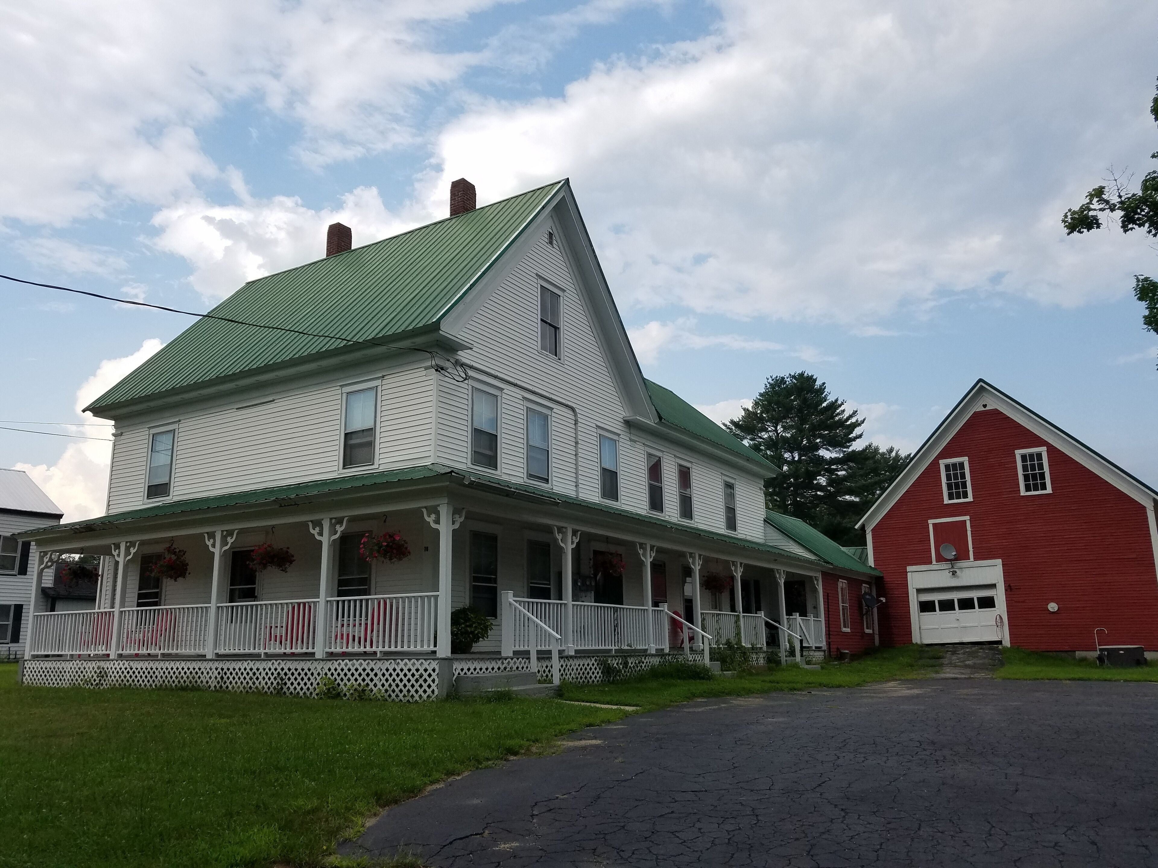 A two-story house with a green roof and a red barn.