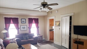 Un salon comprenant un canapé, une table basse, une lampe, un téléviseur et un ventilateur de plafond.