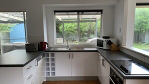 Una cocina moderna con armarios blancos, encimera negra, horno empotrado, microondas y un fregadero con ventana arriba.