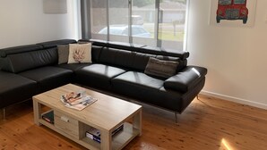 Una sala de estar moderna con un sofá seccional, una mesa de centro de madera y un ventanal con vista a la calle.