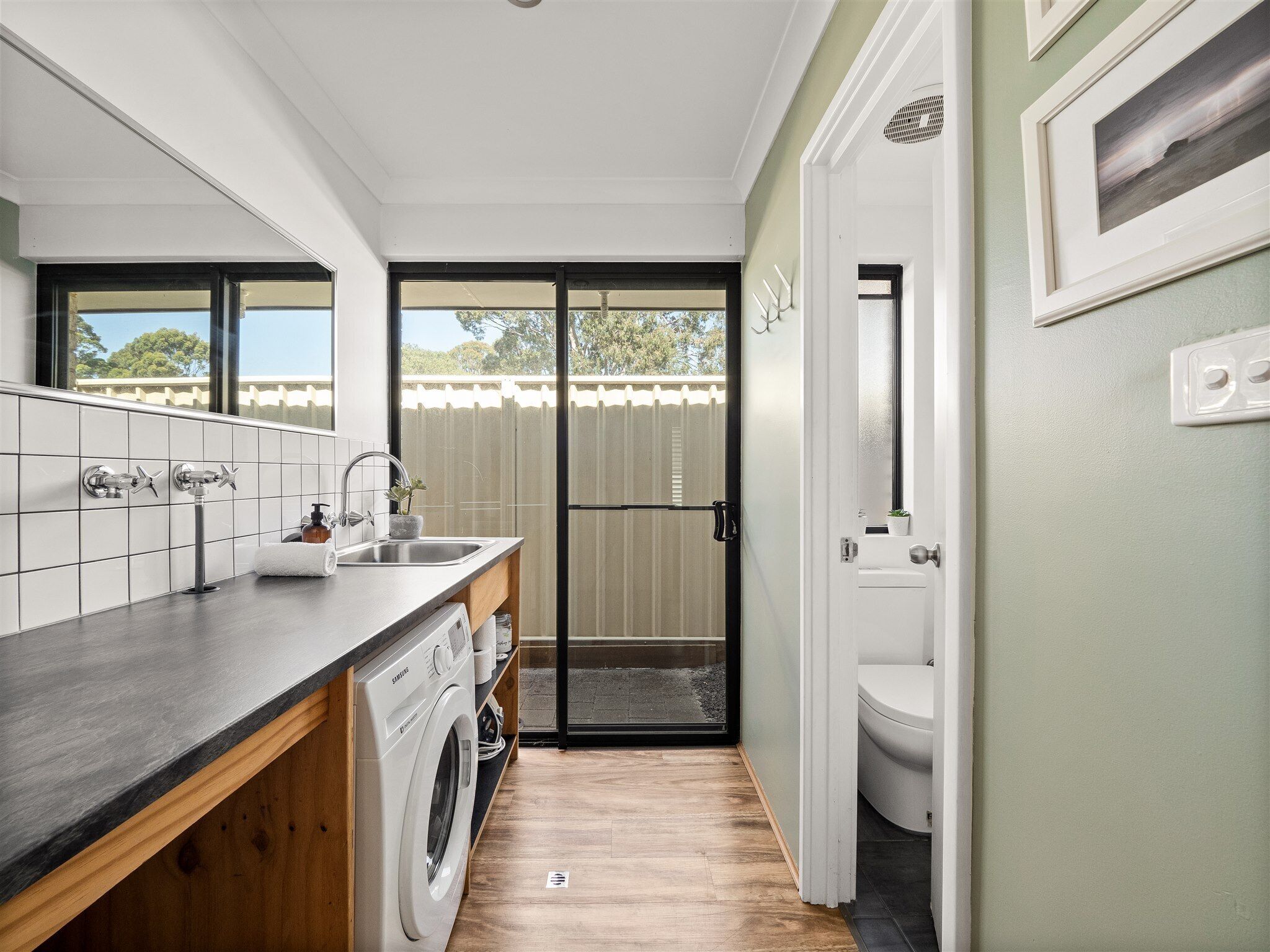 A compact kitchen with a built-in washer, a sink, and a door leading to a toilet.