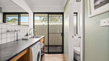 A compact kitchen with a built-in washer, a sink, and a door leading to a toilet.