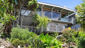 A modern two-story building with balconies, surrounded by lush tropical vegetation. - G SPOT (upper level) WITH SPA (Raglan)