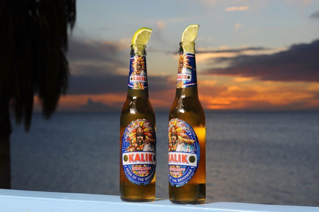 Dos botellas de cerveza Kalik con vista al atardecer.