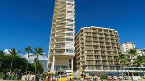 Un hotel alto con varios balcones y ubicación frente a la playa.