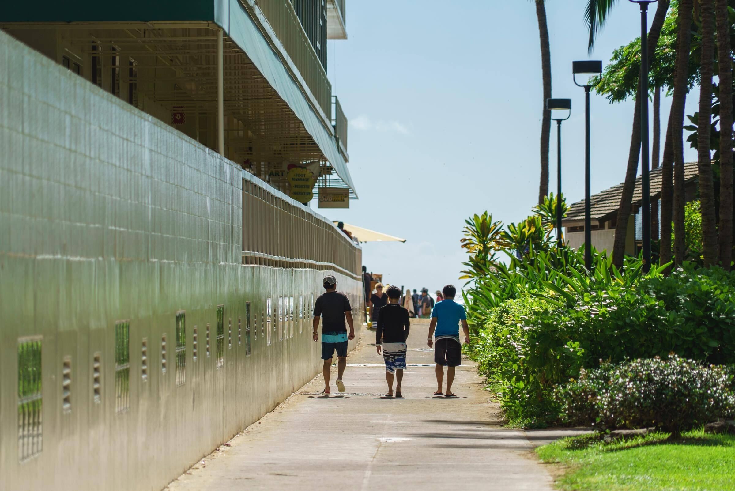 A pathway beside a building with a tiled exterior and a covered upper level.