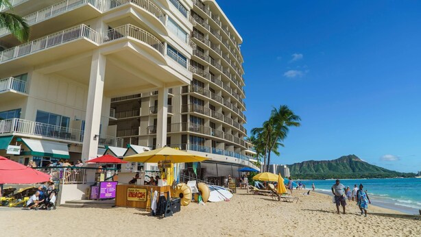 Un hotel frente al mar con varios balcones, sombrillas de playa y vista al océano.