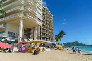 Un hôtel situé en bord de mer, doté de nombreux balcons, de parasols de plage et offrant une vue sur l’océan.