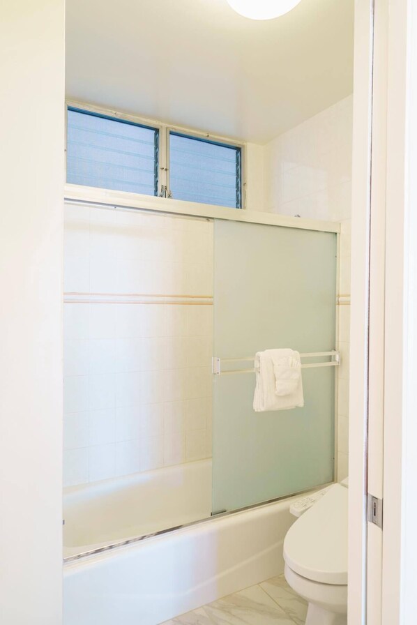 Une salle de bain avec une douche à parois de verre, des toilettes et un porte-serviettes.