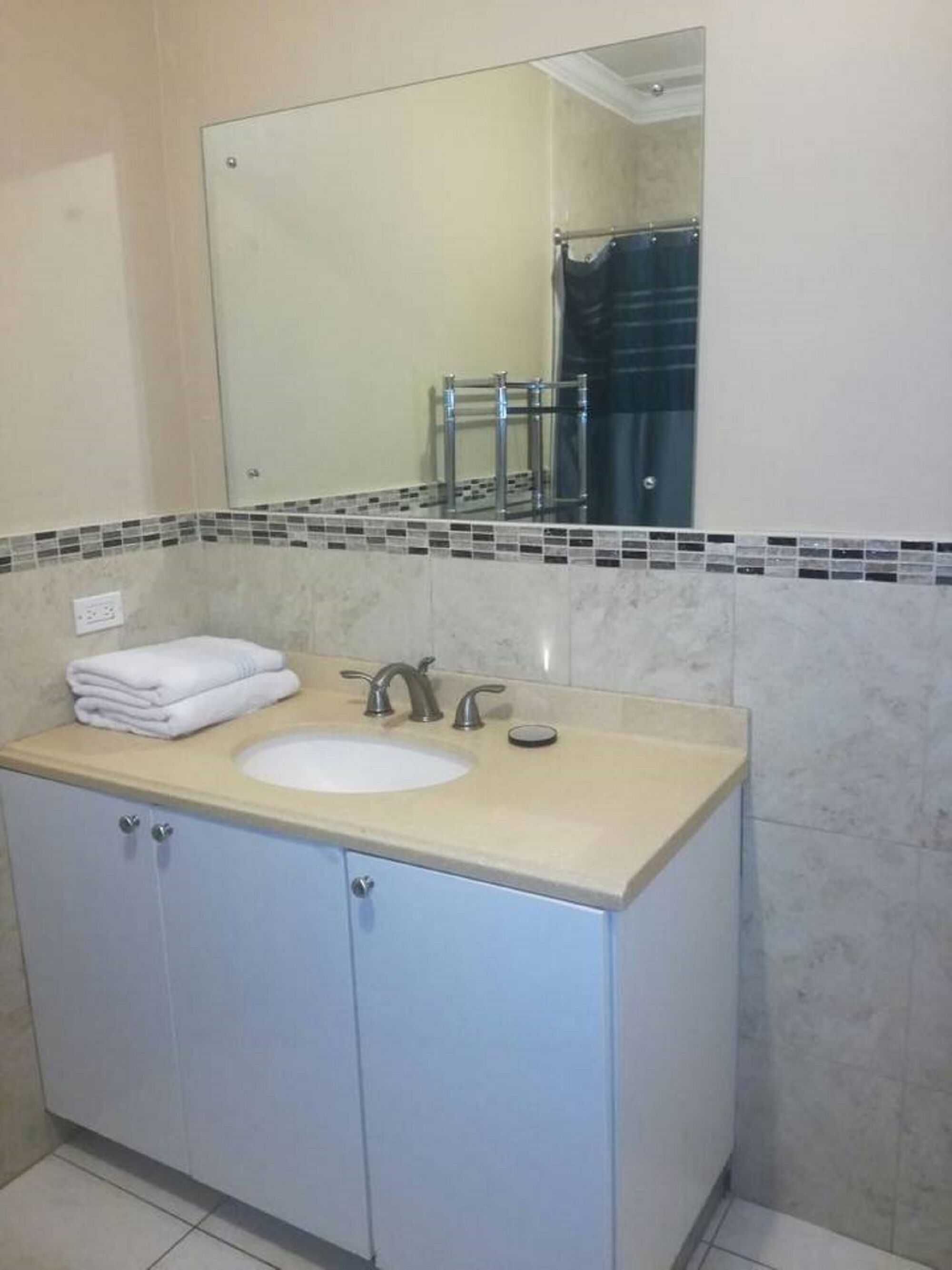 A bathroom with a sink, mirror, and tiled backsplash.