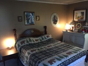A bedroom with a bed, a dresser, a nightstand, a mirror, and wall art.