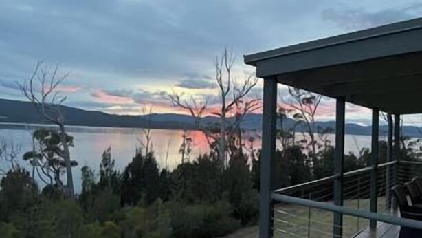 A modern building with a glass facade overlooking a lake and mountains. - Esperance Landing, waterfront luxury (Brooks Bay)