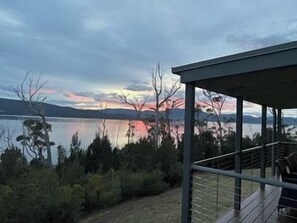 A modern building with a glass facade overlooking a lake and mountains. - Esperance Landing, waterfront luxury (Brooks Bay)