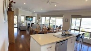 A modern kitchen with a central island, a dishwasher, and a dining area with chairs. - Esperance Landing, waterfront luxury (Brooks Bay)