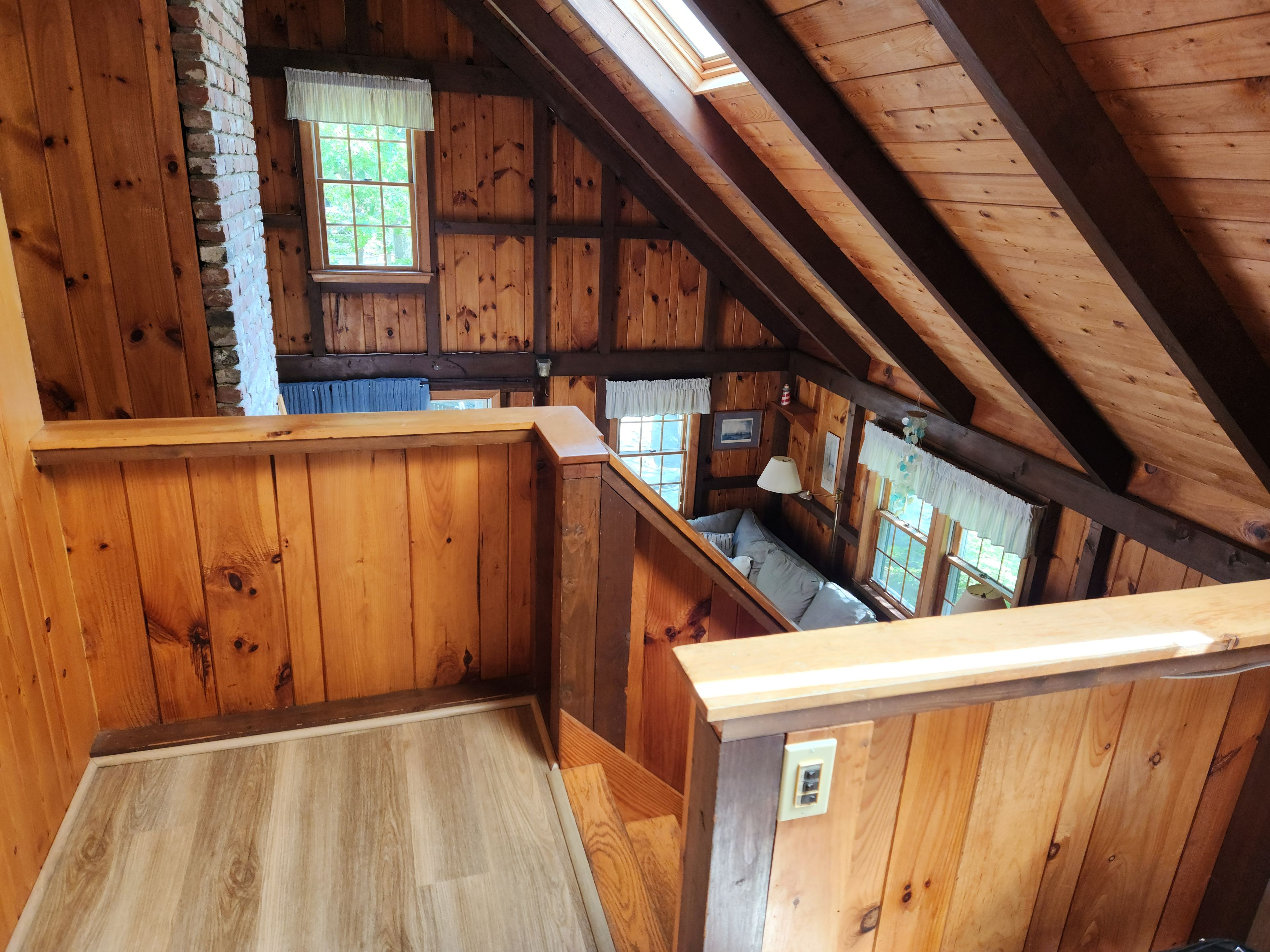 A wooden interior with a sloped ceiling, a window with a view, and a seating area.