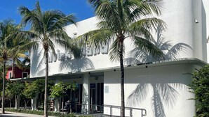 Un edificio moderno con fachada blanca y palmeras al frente.