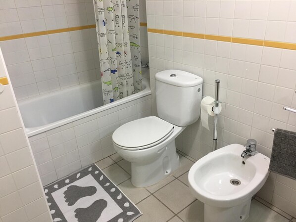 A bathroom with a toilet, bidet, and bathtub.
