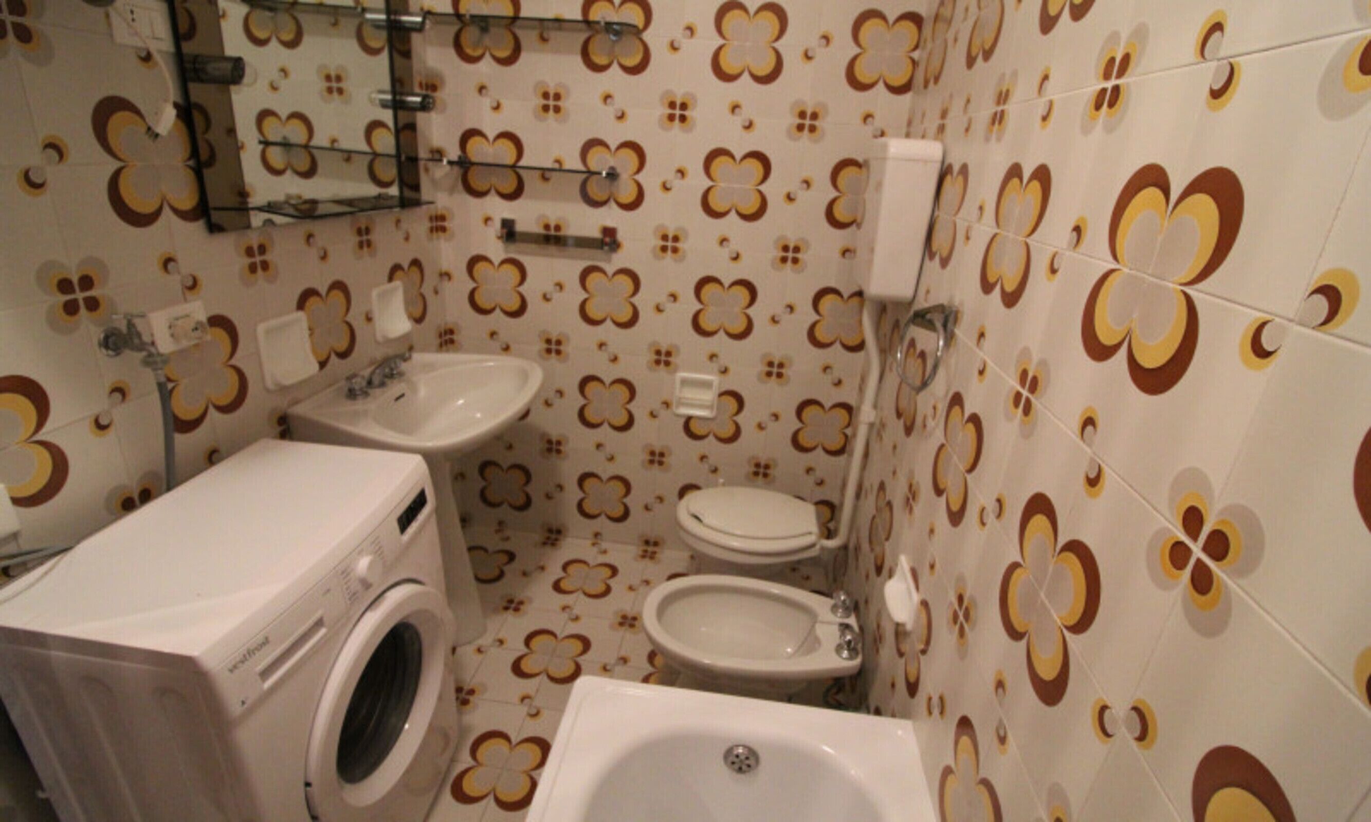 Une petite salle de bain équipée d’un lave-linge, d’un évier, de toilettes et d’un bidet.