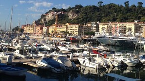 A marina with numerous boats docked, a clear sky, and buildings in the background. - Apartment with a beautiful view in the Port ! (Nice)