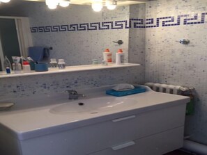A bathroom with a white sink, blue towel, and toiletries on a shelf. - Apartment with a beautiful view in the Port ! (Nice)