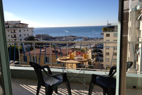 A balcony with a view of the sea and a marina. There are two chairs and a table on the balcony. - Apartment with a beautiful view in the Port ! (Nice)