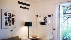 A modern living room with a grey sofa, a small round table, a floor lamp, and a wall-mounted mirror. - three-room apartment with private garden (chiavari)