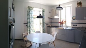 A kitchen with a round table, grey cabinets, and a black countertop. - three-room apartment with private garden (chiavari)