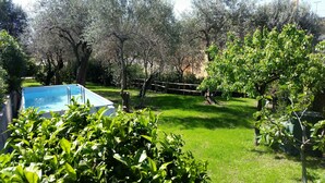 A backyard with a swimming pool, surrounded by trees and a grassy lawn. - three-room apartment with private garden (chiavari)