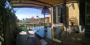 A glass-top table with chairs on a balcony with a view of buildings. - three-room apartment with private garden (chiavari)
