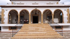 Un bâtiment doté d’un toit en tuiles, de plusieurs arcades et d’un escalier menant à une entrée abritée.