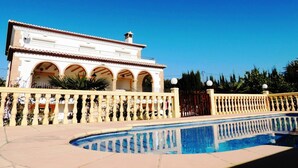 Un grand bâtiment doté d’une piscine, de fenêtres en arc de cercle et d’un toit recouvert de tuiles.