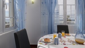 A dining area with a table set for breakfast, including a plate of pastries, a glass of orange juice, and a pitcher of juice. - Holiday house by the sea. (Calheta/ Madeira)