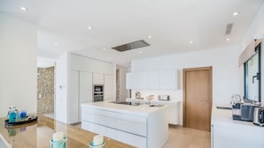 A modern kitchen with white cabinetry, a central island, and a built-in oven.