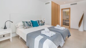 A modern hotel room with a large bed, two pillows, a bedside table with a lamp, and neatly folded towels.