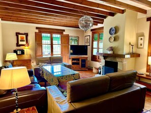 A living room with a sofa, a coffee table, a television, and a fireplace.