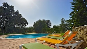 Ein Swimmingpool mit Liegestühlen und einer Steinmauer.