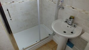 Une salle de bain avec une douche à parois de verre, un lavabo blanc et des toilettes.