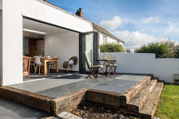 An open-plan living area with a dining table and chairs, a sofa, and a small seating area with a chair and a table. - Luxury Cottage, less than 5 mins walk to the North Cornwall Coast (Bude, Cornwall)
