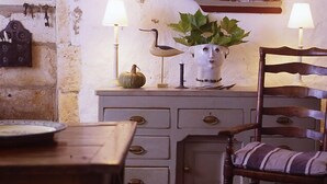 A rustic kitchen with a wooden table, a chair, a cabinet with drawers, a potted plant, and a decorative ship model. - Exquisite Farmhouse & Heated Pool (Lusignac)