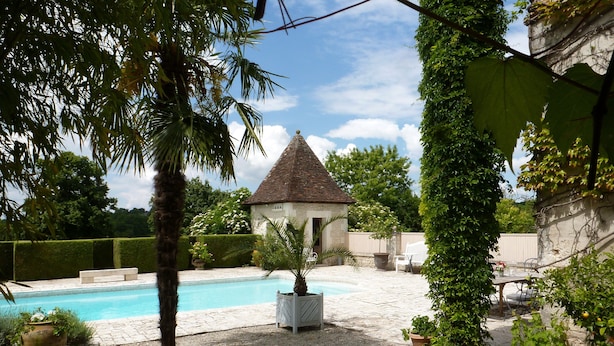 A backyard with a swimming pool, a small gazebo, and a stone building partially covered by ivy. - Exquisite Farmhouse & Heated Pool (Lusignac)