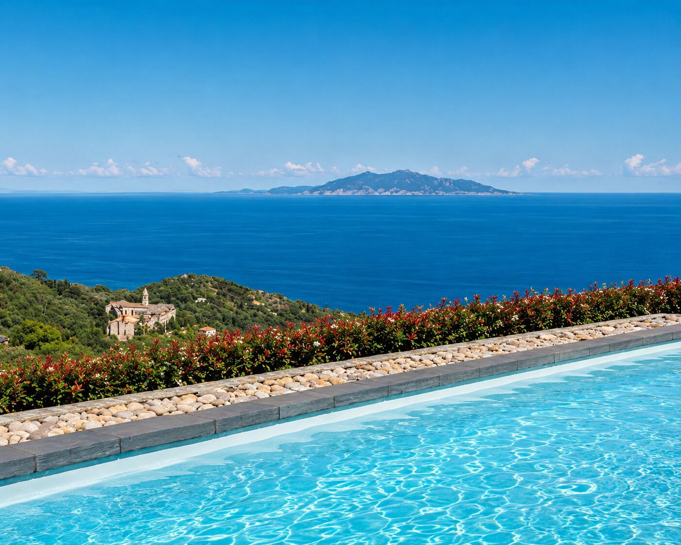 A swimming pool with a view of the sea and a distant mountain.