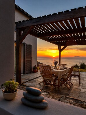 Une terrasse avec une table dressée pour le dîner, offrant une vue imprenable sur le coucher du soleil.